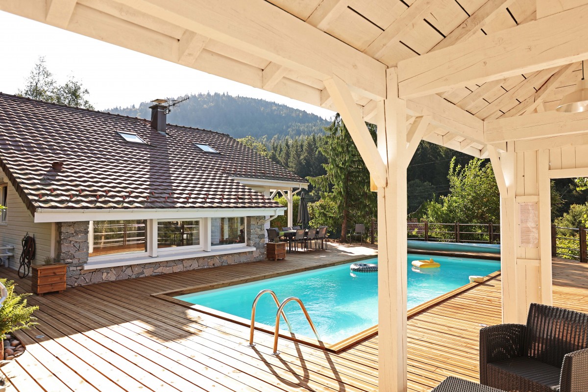 Vue de la terrasse et de la piscine depuis l'entrée de la salle de sport du gîte